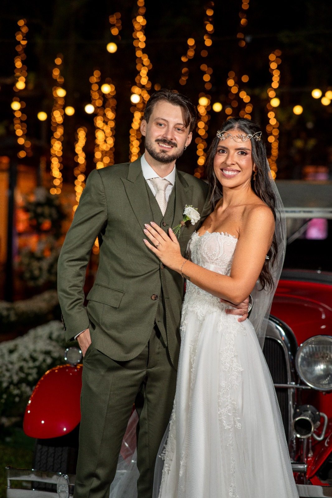 Noivos sorrindo diante das luzes do jardim